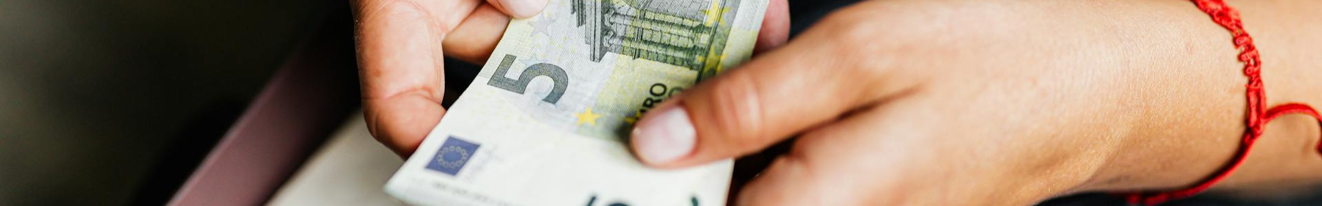 Mains d'une personne tenant des billets de 5€