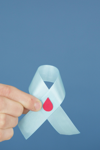 Main qui tient un ruban, symbole du don du sang